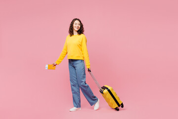 Traveler woman wear yellow casual clothes hold bag passport ticket isolated on plain pastel pink...