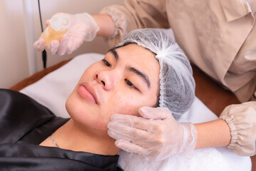 Rubbing in hyaluronic acid serum prior to a high frequency facial treatment at a spa.