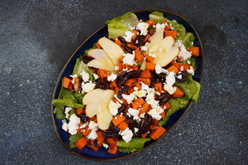 Fresh salad made of baked sweet potatoes, fresh apples, pecan and feta cheese, lettuce.