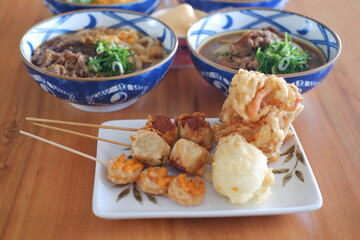fried dumpling in a white plate on wooden table and Rice noodle with beef in bowl