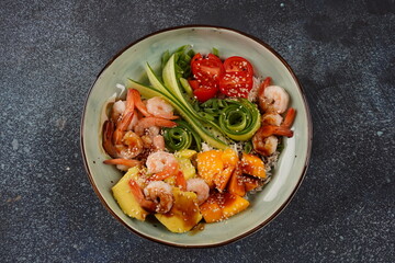 Fresh seafood recipe. Shrimps poke bowl with rice, green onions, tomatoes,avocado,mango. Food concept poke bowl on gray background