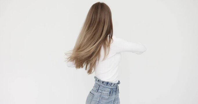 Young woman performs warming up exercise rotating upper body against white wall. Female tries to cope with pain in back in office slow motion