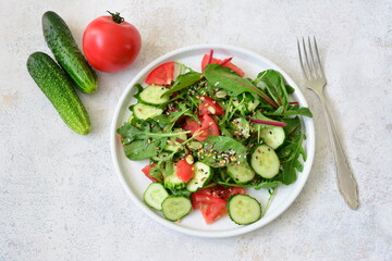 a plate of salad with cucumber and tomatoes and a fork on the right