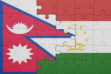 puzzle with the colourful national flag of nepal and flag of tajikistan .