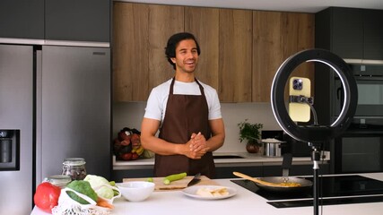 Professional chef cooking in a modern kitchen, filming a vlog with a smartphone. Fresh vegetables being chopped for a healthy meal