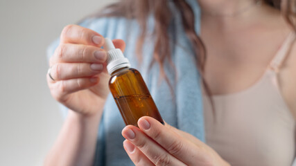 Fototapeta premium Close-up of hands holding a face serum bottle for hydration, showcasing skin care aesthetics and strategies for maintaining healthy skin.