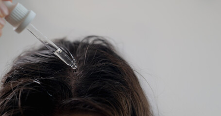 Cosmetologist performing a scalp treatment with hair growth oil, promoting healthier and stronger hair development.