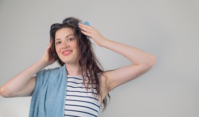 Young girl with dark curly hair using a head massager or brush to stimulate hair growth, on a white background.