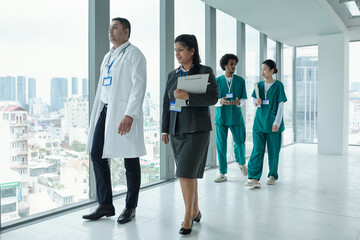 Manager of clinic talking to doctor while they walking along the hospital corridor