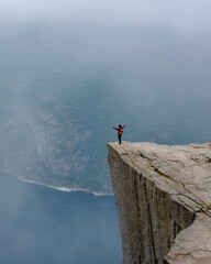 Daring Adventurer Standing on Pulpit Rock Overlooking Norway's Majestic Fjords, Preikestolen Norway