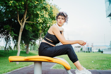 Young caucasian woman is taking a break from training in park