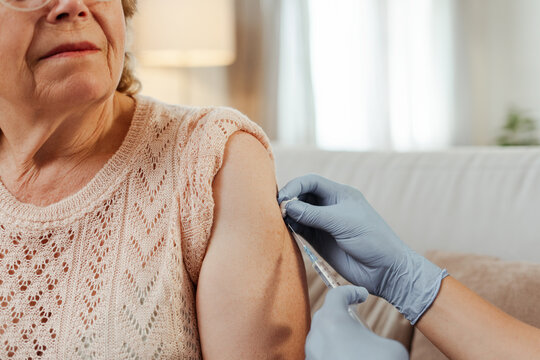 Doctor giving vaccine to senior woman at home