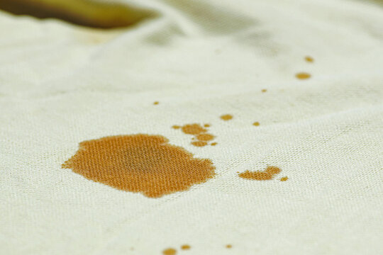 Large coffee stain on light cotton fabric. Close-up photo of clothes where the drink was spilled. Bad day - troubles during lunch.