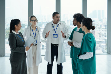 Team of doctors discussing diagnosis together while standing in hospital corridor