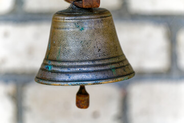 Close-up of metal bell with clapper and defocus brick wall background at Swiss farm on a sunny...