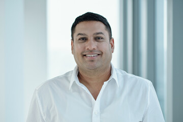 Portrait of mature businessman smiling at camera while standing in office