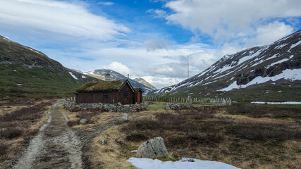 Serene Mountain Landscape With Traditional Cabin Surrounded by Snow-Capped Peaks in Norway