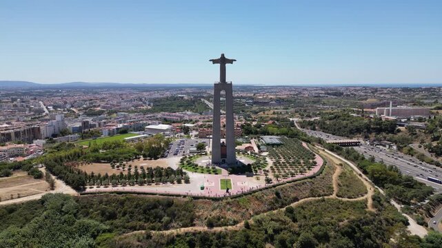 Drone flying towards the Sanctuary of Christ the King shrine on a sunny day in Almada, Portugal