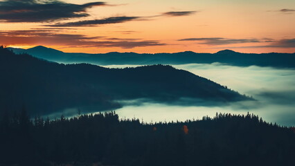 Fototapeta premium The sun's first rays light up carpathian peaks, casting shadows on slopes with fog adding mystery and serenity