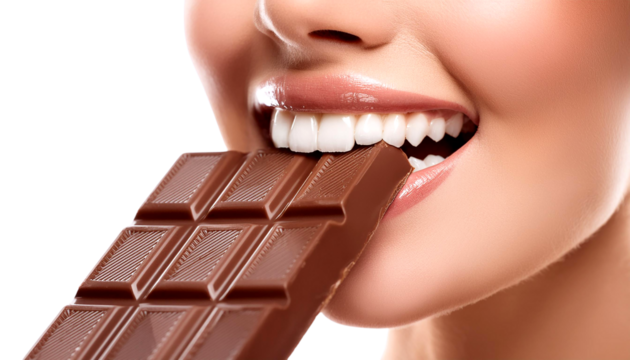 A joyful woman playfully bites into a bar of chocolate, showcasing her bright smile and love for sweets.