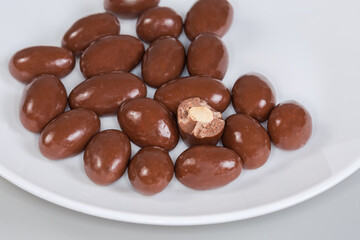 Almonds covered with milk chocolate on dish, fragment close-up