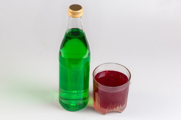Green non-alcoholic drink in bottle, red fruit drink cup