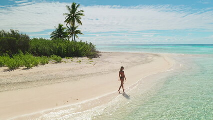 Woman walks on a beautiful maldives beach, enjoying the serene tropical paradise. Palm trees, turquoise waters, and a sunny sky create a peaceful scene