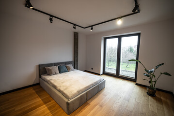  Interior of a newly built house, bedroom with a large, comfortable bed with plush pillows and soft...