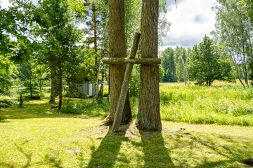 A large wooden cross in the park outside the church. A wooden cross between two trees.