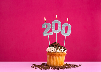 Birthday celebration with candle number 200 - Chocolate cupcake on pink background