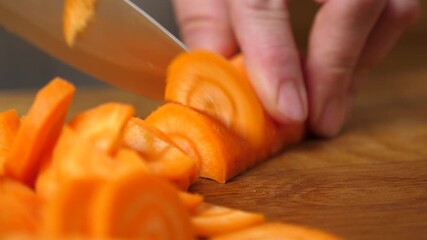 Raw peeled carrots are cut into cubes with a knife. Preparation of a vegetable dish.