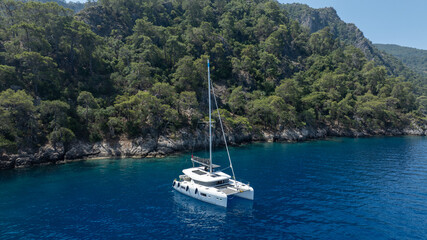 Aerial view of a catamaran sailing smoothly on the clear waters.
