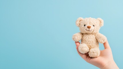 Obraz premium Tender Comfort of Childhood - Hand holding small teddy bear on soft blue background symbolizing warmth and nostalgia, Generative Ai