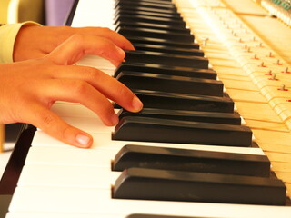 Close-up of a child's hands playing a piano.
