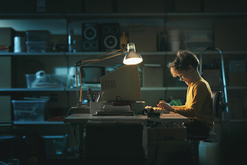 Cute boy using an old computer in his garage
