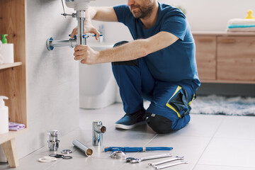 Expert plumber working on a bathroom sink drain