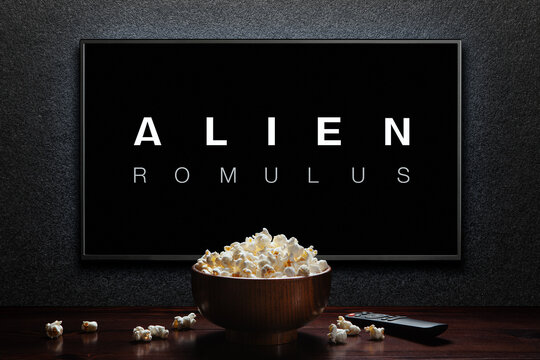 Alien Romulus trailer or movie on TV screen. TV with remote control and popcorn bowl. Astana, Kazakhstan - July 31, 2024.