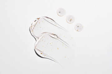 Smears and drops with skin care cosmetics - 24k gold hyaluronic gel serum and drops of liquid. Cosmetic background flat lay