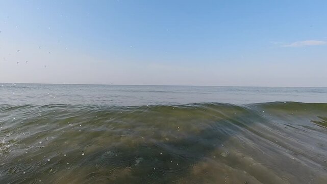 A young couple runs into the sea on the first day of their vacation, kicking up the spray behind them. Slow motion. Water games. Vacation and recreation. Slow Motion