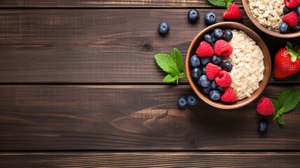 Naklejka premium A wooden table with a bowl of oatmeal and fresh berries, viewed from above