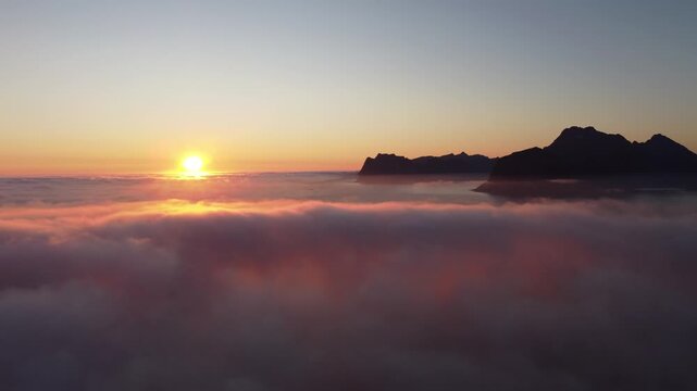 Dreamy aerial view over clouds with midnight sun in Lofoten, Northern Norway