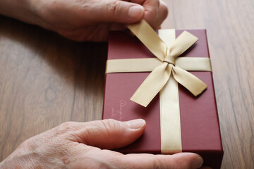 プレゼントのりぼんをほどく高齢女性の手元