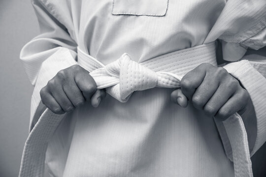 black and white Kid in martial arts taekwondo or karate dobok uniform and holding belt