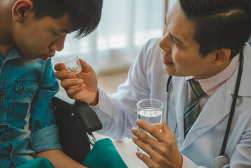 Doctor helping a young patient take medication in a hospital. Medical professional providing care and support in a clinical setting.