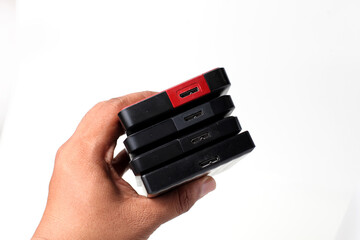 hand holding a stack of external hard disks on a white backround