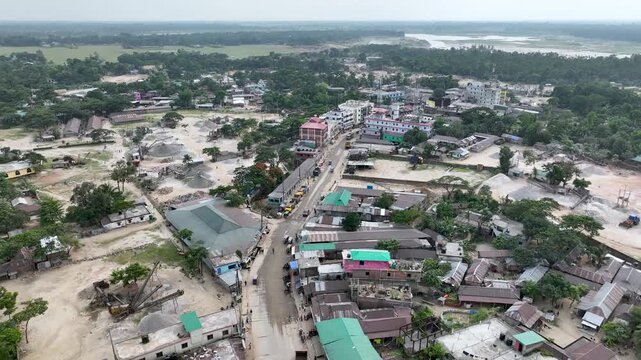 aerial captures a winding road through a verdant landscape with scattered buildings,stretching into the horizon.