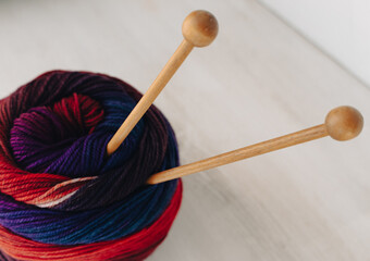 Bright colours fabric ball with wooden knitting needles. Colourful wool yarn with knitting needles on white background. Needlework with copy space. Knitting hobby. Knit tools. Knitted fashion. 