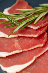 sliced ham with bacon on a board