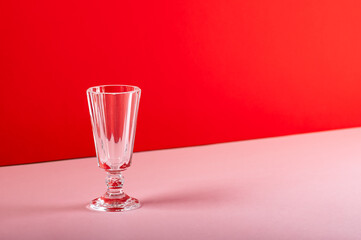 Empty glass shot glass on red background.