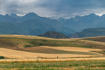 Panoramic view of mountains and fields in a mountain valley. Dramatic stormy sky. Organic farming....